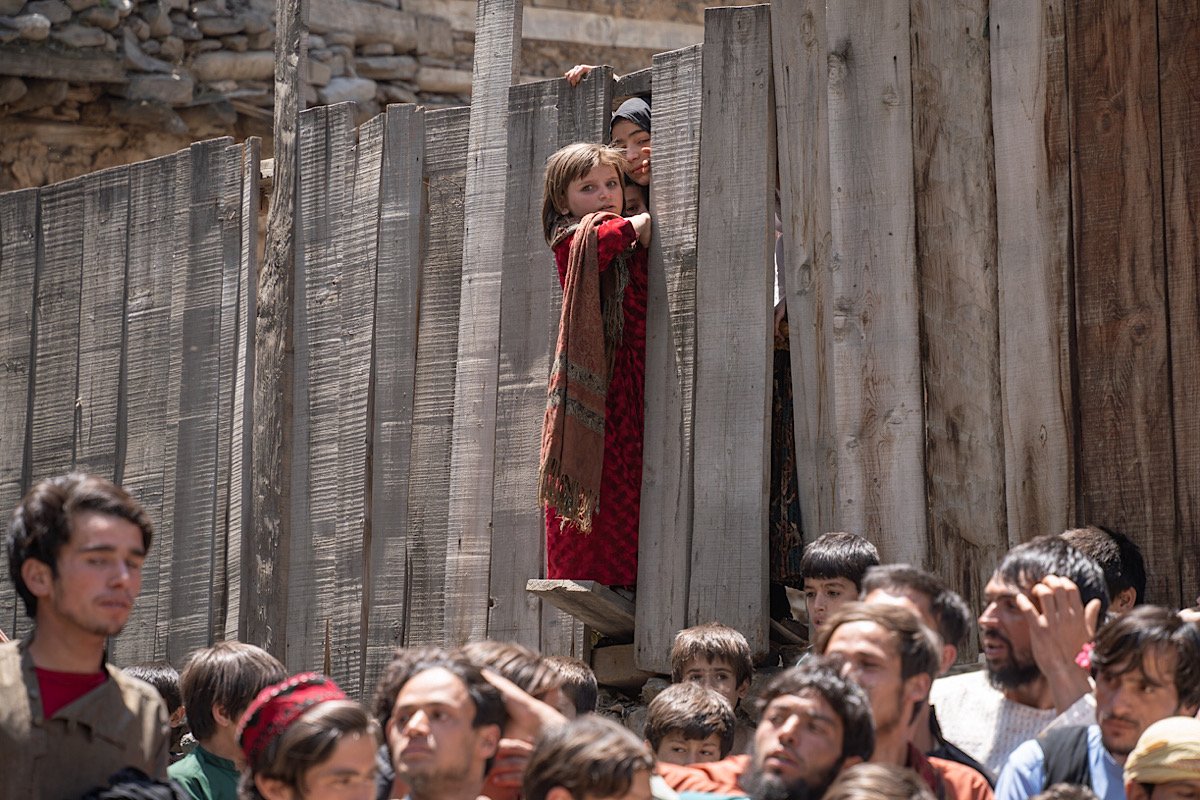 A young Nuristani girl peers though an opening in a fence. Image by author