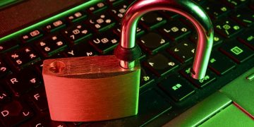 An open padlock sitting on a keyboard in red and green tones