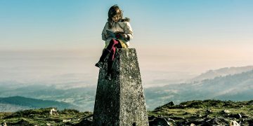 Welsh publishing: a girl sitting reading atop a stone plinth on a Welsh mountain