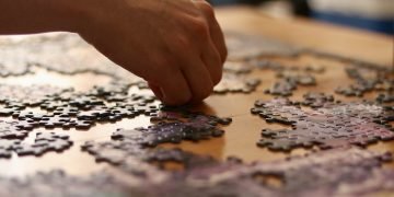 Language: a hand working on an incomplete jigsaw puzzle