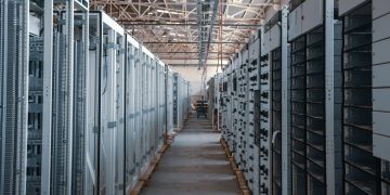 Server room aisle with metal equipment racks.